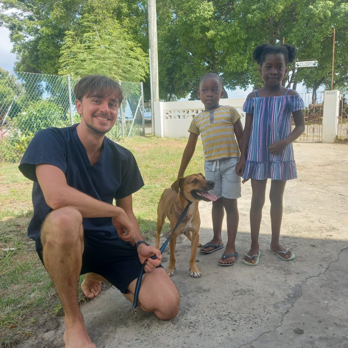 A CAH volunteer with children and a dog during a community outreach visit