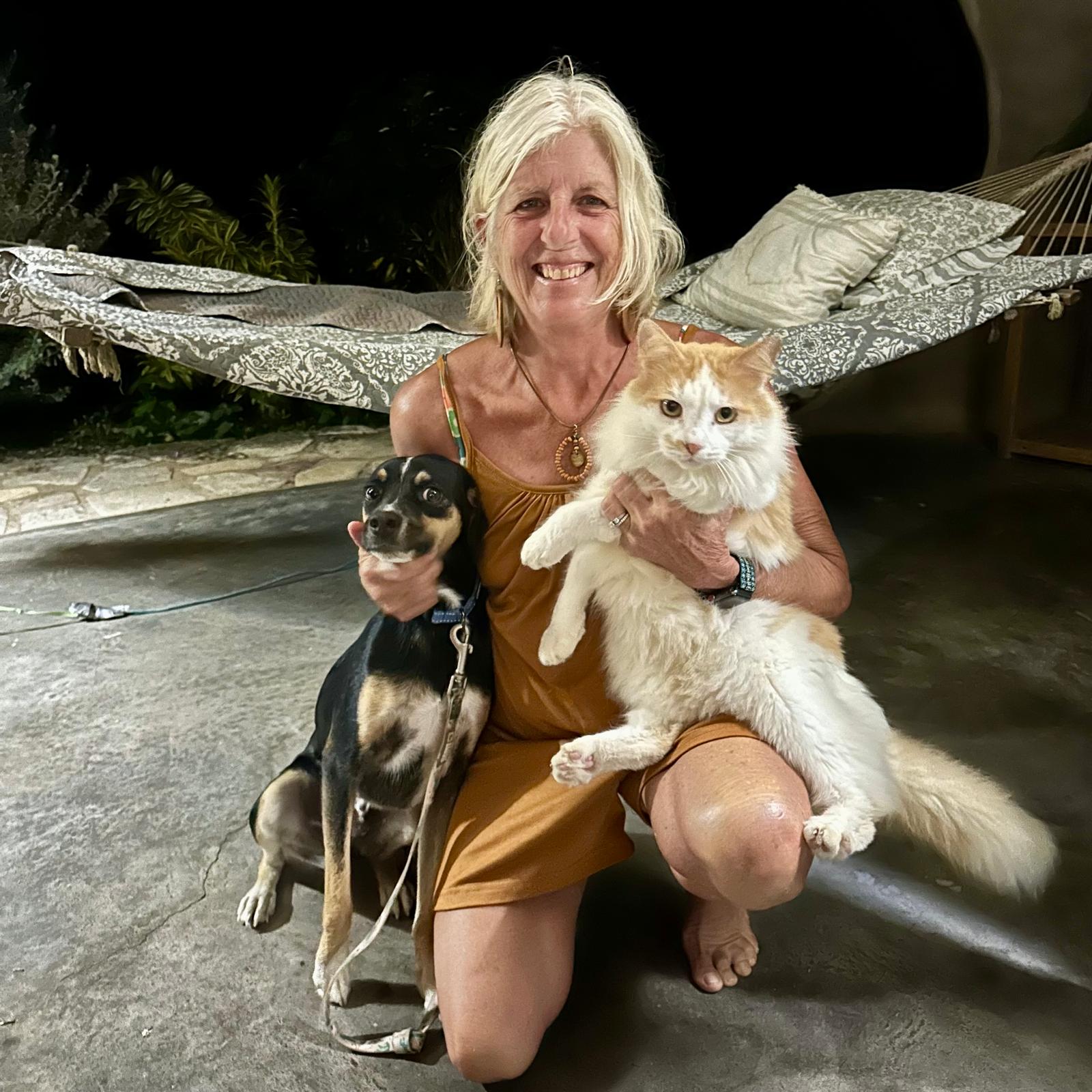 A CAH volunteer relaxing in a hammock with a rescued cat and dog